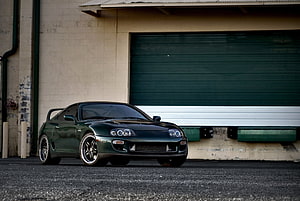 Dark Green Toyota Supra MK4 Parked in Front of Industrial Garage Door HD wallpaper