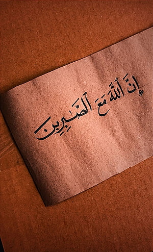 Handwritten Arabic Calligraphy on Textured Beige Paper with Warm Brown Background HD phone wallpaper