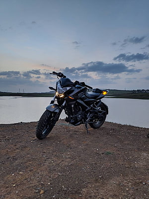 Black Bajaj Pulsar NS200 Motorcycle Parked on Gravel Shore at Dusk HD phone wallpaper