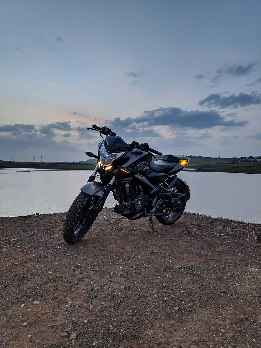 Black Bajaj Pulsar NS200 Motorcycle Parked on Gravel Shore at Dusk HD phone wallpaper