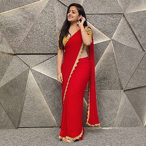 Vaishnavi Chaitanya in a red and gold saree against a geometric stone wall HD phone wallpaper