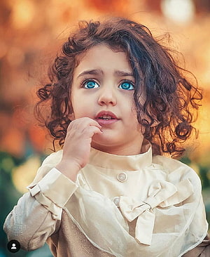 Anahita Hashemzadeh Portrait: Curly-Haired Toddler with Blue Eyes in Vintage Blouse HD phone wallpaper