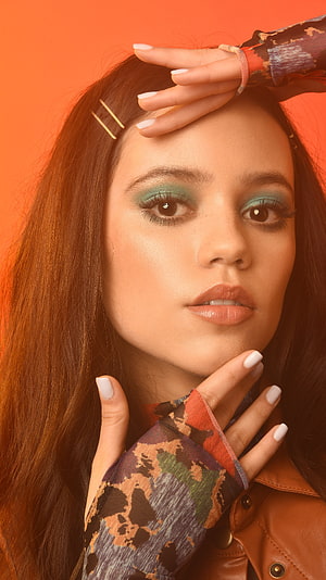 Jenna Ortega Portrait with Teal Eyeshadow and Camouflage Sleeves on Orange Background HD phone wallpaper