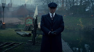Peaky Blinders Tommy Shelby in Dark Overcoat and Flat Cap in Misty Industrial Setting HD wallpaper