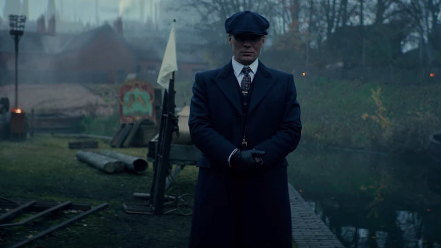 Peaky Blinders Tommy Shelby in Dark Overcoat and Flat Cap in Misty Industrial Setting HD wallpaper
