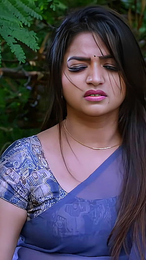 Nithya Ram in a Blue Patterned Saree with a Gold Necklace and Natural Green Foliage Background HD phone wallpaper