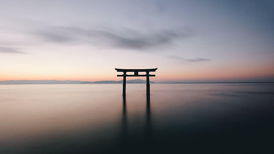 Silhouette of a Japanese Torii Gate Standing in Calm Water at Dusk HD wallpaper
