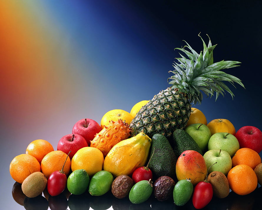 Vibrant tropical fruit arrangement with pineapple, mango, avocado, and citrus on a dark background HD wallpaper