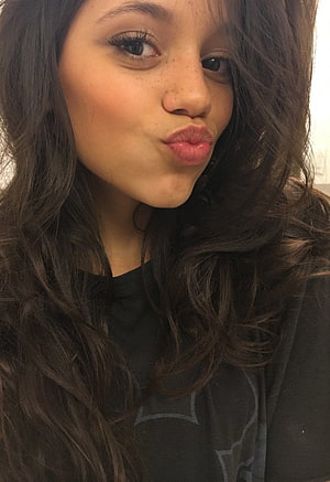 Jenna Ortega Close-Up Portrait With Long Wavy Hair And Playful Expression HD phone wallpaper