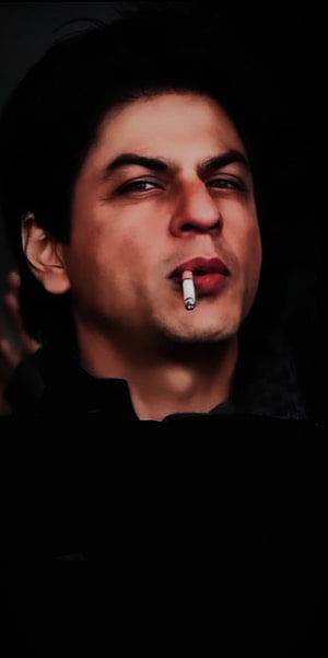 Shah Rukh Khan in a moody close-up portrait holding a cigarette against a dark background HD phone wallpaper