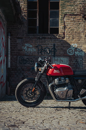 Red Royal Enfield GT 650 Motorcycle Parked on Cobblestones Against a Graffiti Brick Wall HD phone wallpaper