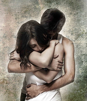 Emotional Embrace of a Young Couple Against a Textured Grunge Wall HD phone wallpaper