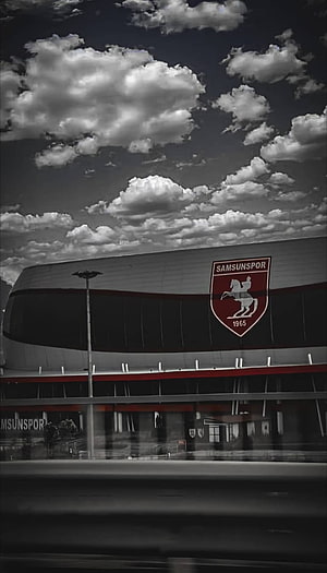 Samsunspor Stadium Exterior with Red Crest and Dramatic Cloudy Sky HD phone wallpaper