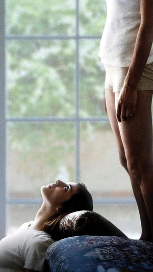 Dogtooth Movie Still: Woman Lying on Floor Gazing Up at Standing Figure by Window HD phone wallpaper