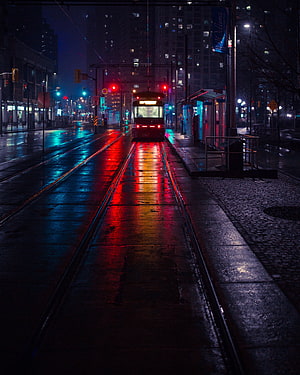 Rainy Night City Street with Glowing Tram Tracks and Wet Asphalt Reflections HD phone wallpaper