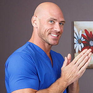 Johnny Sins in Blue Medical Scrubs Smiling with Hands Together in Front of Floral Canvas Art HD phone wallpaper