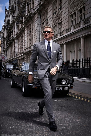 Daniel Craig as James Bond in a grey suit walking past a classic Aston Martin in London HD phone wallpaper