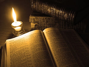 Open Bible and Candlelight with Stacked Leather Books in Warm Dim Lighting HD wallpaper