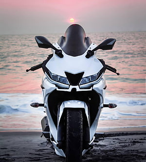 White Yamaha R15 V3 sport bike parked on a beach at sunset with ocean waves in the background HD phone wallpaper