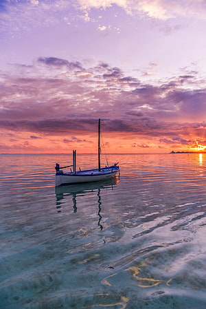 Solitary Sailboat Drifting on Calm Turquoise Waters During a Vibrant Sunset HD phone wallpaper