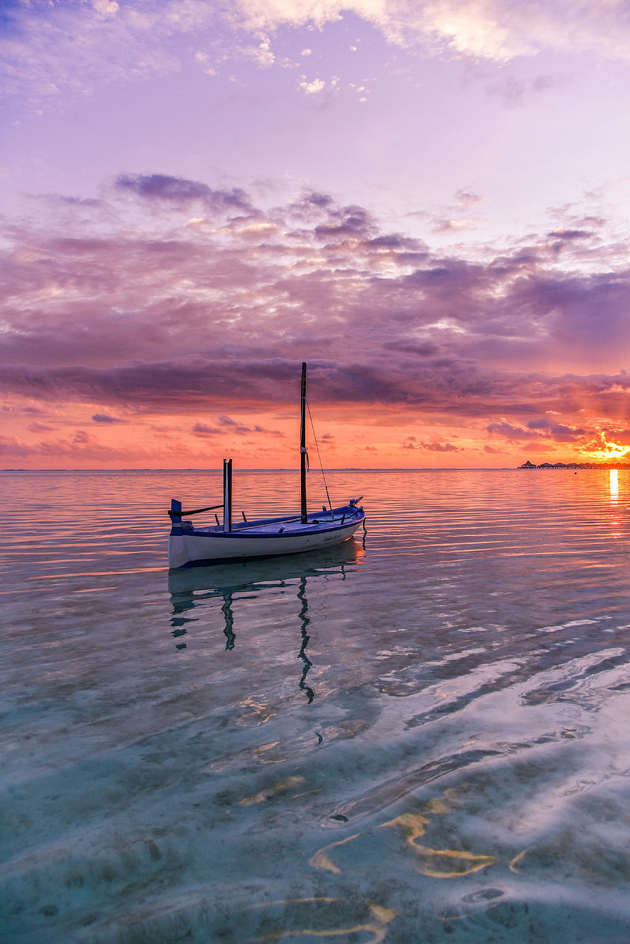 Solitary Sailboat Drifting on Calm Turquoise Waters During a Vibrant Sunset HD phone wallpaper