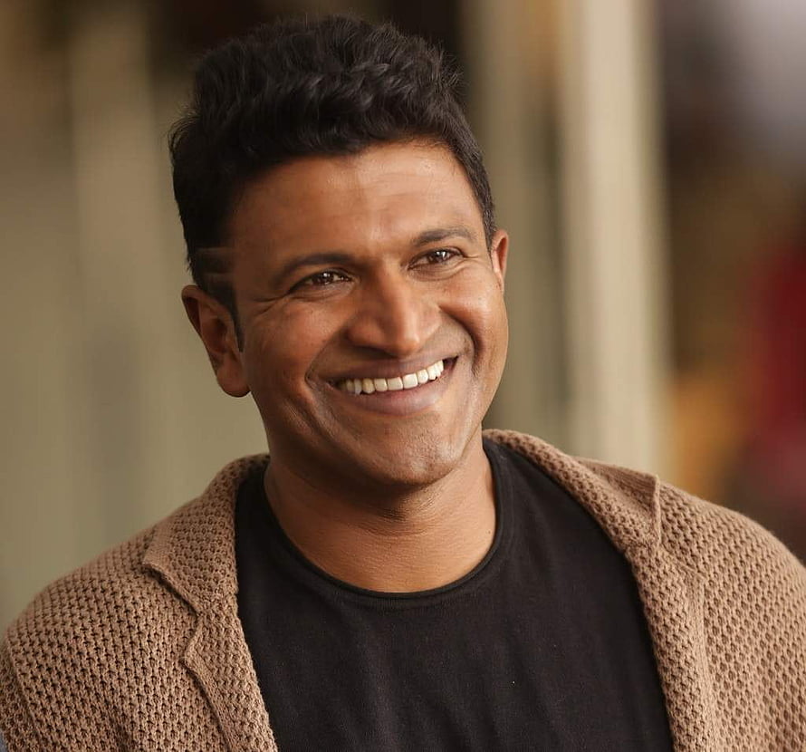 Puneeth Rajkumar smiling portrait in a brown knit cardigan and black t-shirt HD wallpaper
