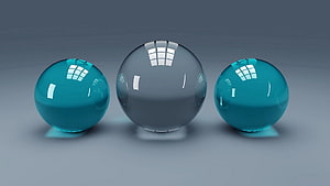 Three glossy glass spheres in teal and clear tones on a neutral gray studio background HD wallpaper