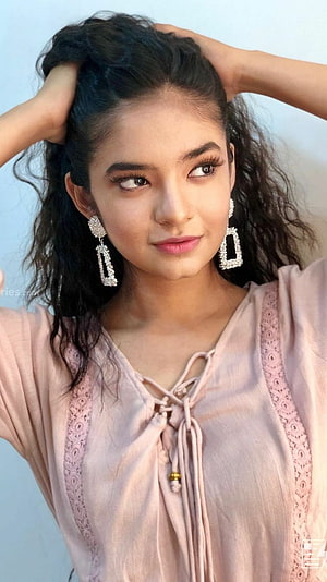 Anushka Sen in a soft pink lace-up top with statement earrings and wavy hair HD phone wallpaper