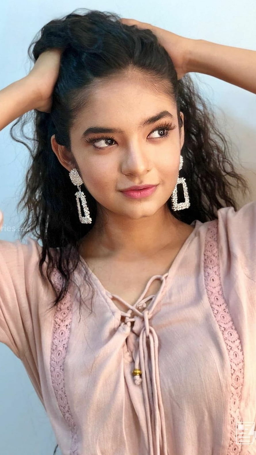 Anushka Sen in a soft pink lace-up top with statement earrings and wavy hair HD phone wallpaper