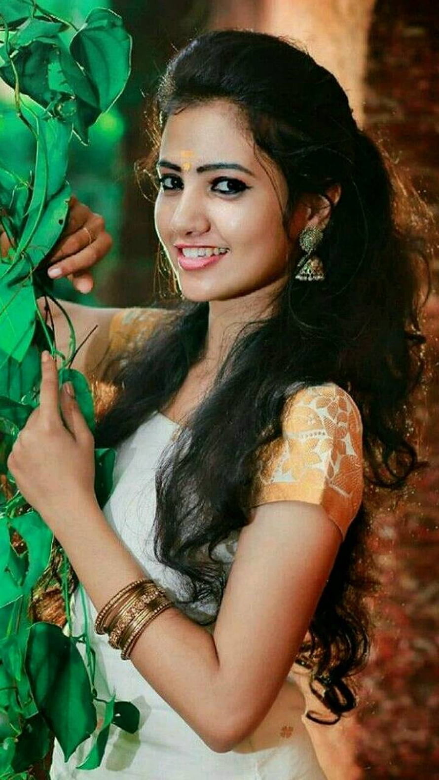 Smiling Indian Woman in Traditional Attire Holding Green Leaves HD phone wallpaper