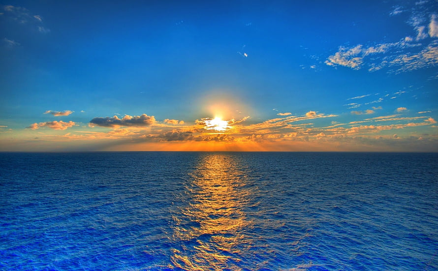 Golden sunset over a calm ocean with a shimmering sun reflection on the water surface HD wallpaper