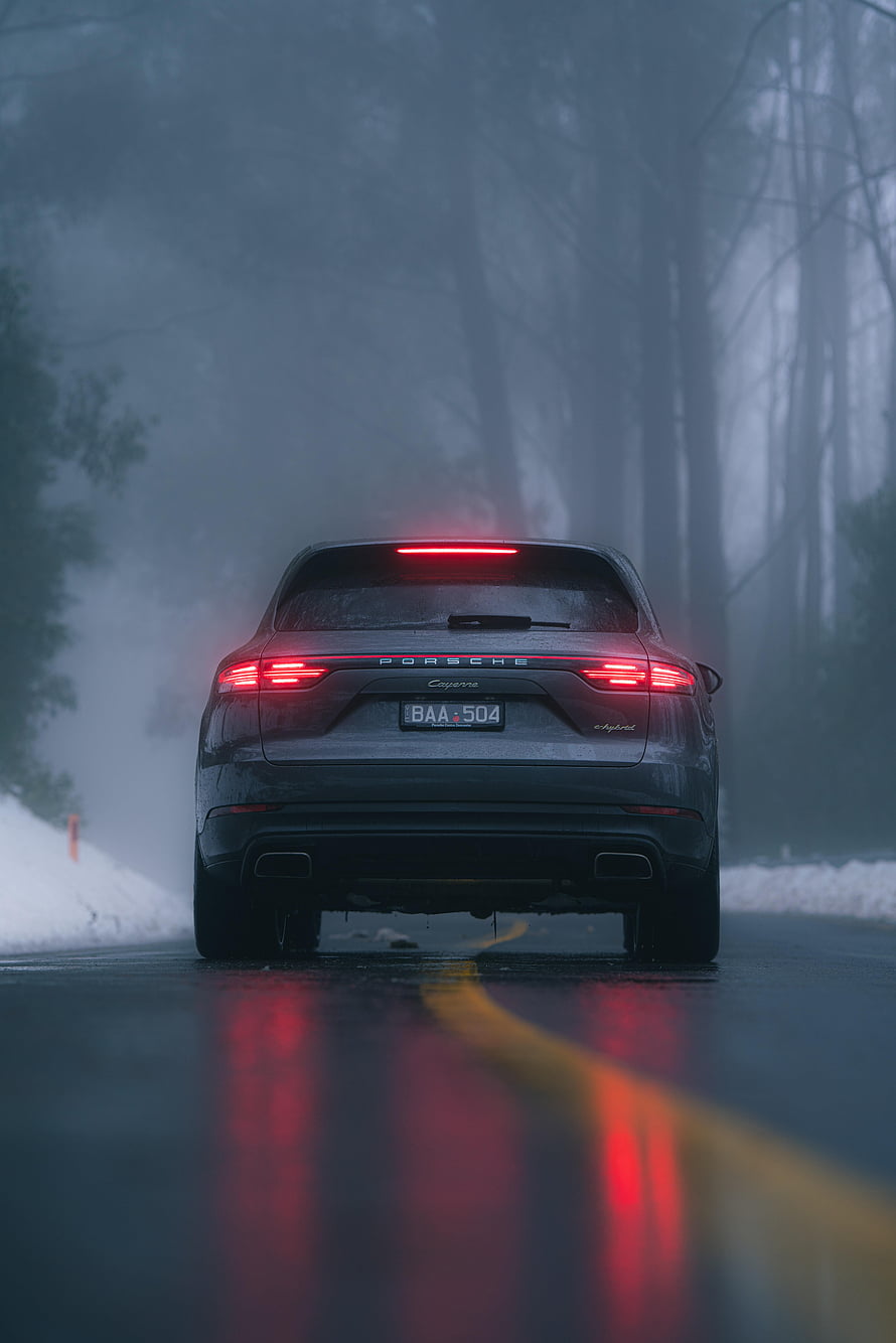 Rear View of a Grey Porsche Cayenne Hybrid on a Wet, Foggy Forest Road HD phone wallpaper
