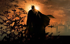 Batman Silhouette Standing Before a Swarm of Bats Against a Dramatic Orange Sky HD wallpaper