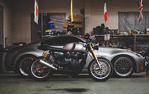 Custom Cafe Racer Motorcycle Parked in Front of Silver Sports Car in Garage HD wallpaper
