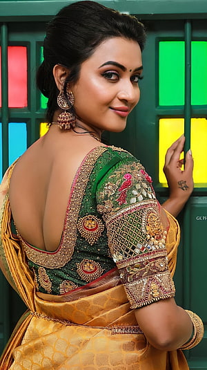 Janani Ashok Kumar in an ornate green and gold embroidered saree with traditional jewelry HD phone wallpaper
