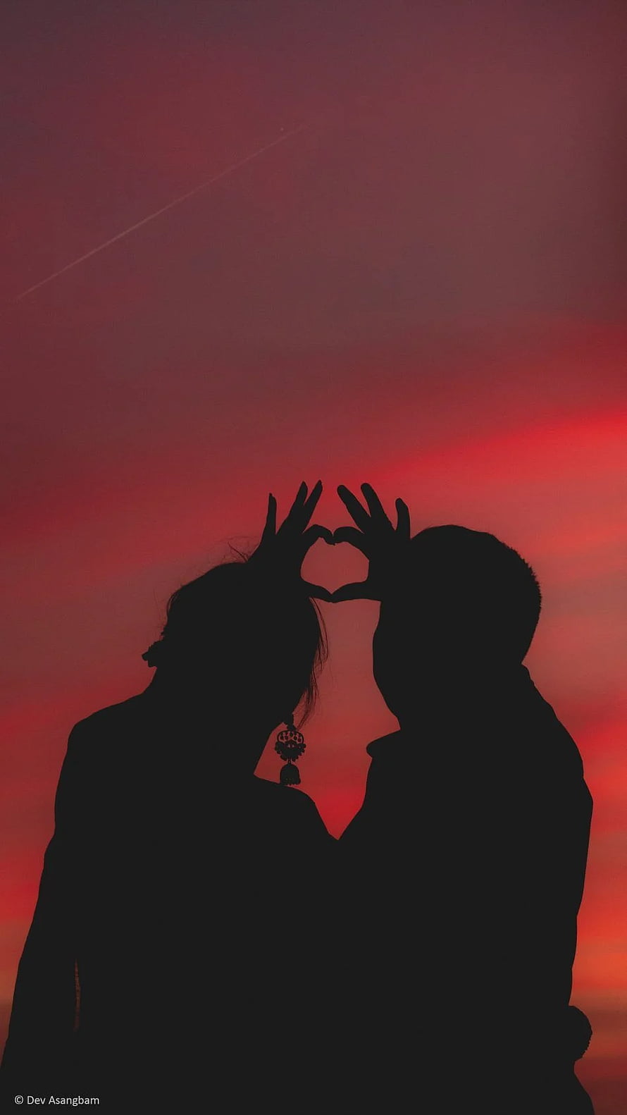 Silhouette of a couple forming a heart shape against a vibrant red sunset sky HD phone wallpaper
