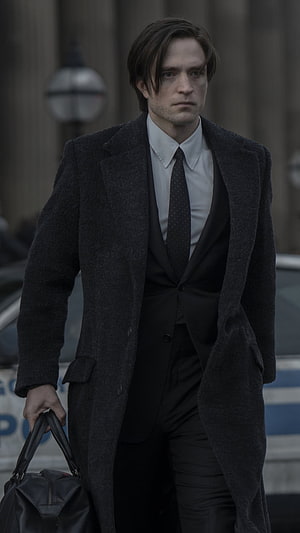 Robert Pattinson as Bruce Wayne in a dark overcoat and suit carrying a leather bag HD phone wallpaper
