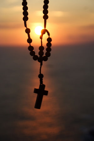 Silhouette of a Catholic rosary with cross against a golden sunset sky HD phone wallpaper