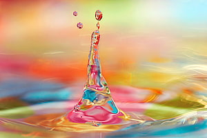 Vibrant Water Splash with Prismatic Droplets Against a Soft Multicolored Gradient Background HD wallpaper