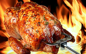 Glossy Grilled Whole Chicken on Rotisserie Skewer Against Fiery Flame Background HD wallpaper