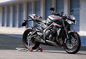 Triumph Street Triple RS sport motorcycle in silver and red parked on a racetrack HD wallpaper