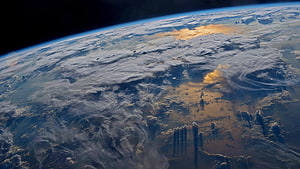 Earth from orbit with swirling cloud patterns and atmospheric haze over landmasses HD wallpaper