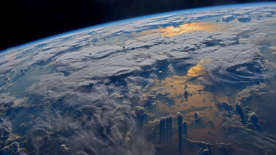 Earth from orbit with swirling cloud patterns and atmospheric haze over landmasses HD wallpaper
