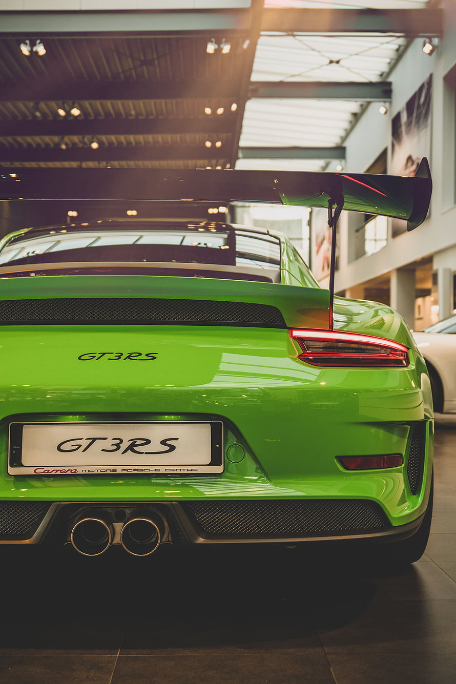Rear View of a Green Porsche 911 GT3 RS with Large Rear Wing in a Showroom HD phone wallpaper