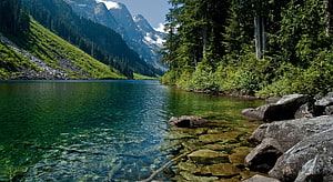 Serene Alpine Lake with Crystal Clear Water and Lush Forested Mountains HD wallpaper