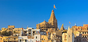Dwarkadhish Temple in Dwarka, Gujarat, India with traditional shikhara spire and saffron flags against a clear blue sky HD wallpaper