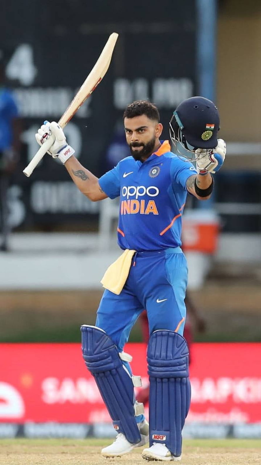 Virat Kohli in India ODI kit raising bat and helmet on the cricket field HD phone wallpaper