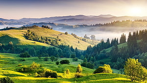 Misty Morning Over Rolling Green Hills and Distant Mountain Ranges HD wallpaper
