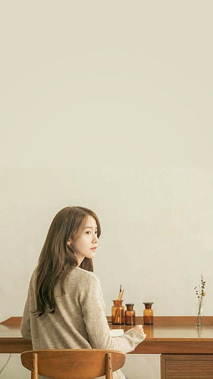 Yoona from SNSD in a Soft Beige Sweater Seated at a Wooden Desk in a Minimalist Room HD phone wallpaper