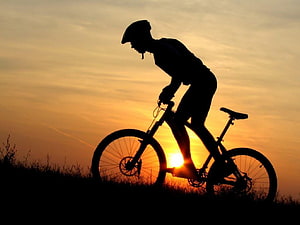 Mountain Biker Silhouette Against Golden Sunset Sky HD wallpaper